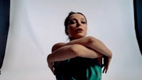 a woman in a green dress is posing in front of a white background