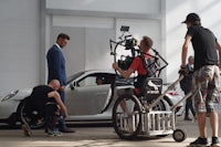 a man in a wheelchair is filming a porsche 911