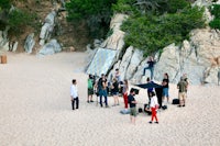 a group of people standing on a sandy beach