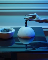 a woman's hand is touching a bowl on a table