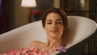 a woman is laying in a bathtub filled with rose petals