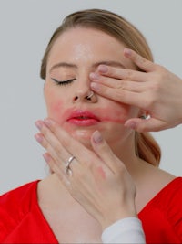 a woman is touching her face with her hands