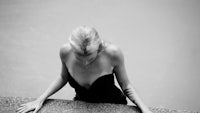 a black and white photo of a woman leaning against a wall