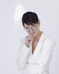 a woman wearing glasses and a white suit