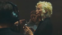 a woman with blonde hair is talking to someone in a recording studio